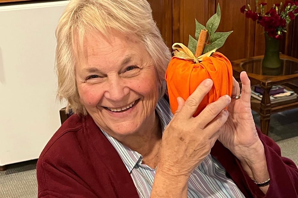 A resident smiling while holding an orange decoration