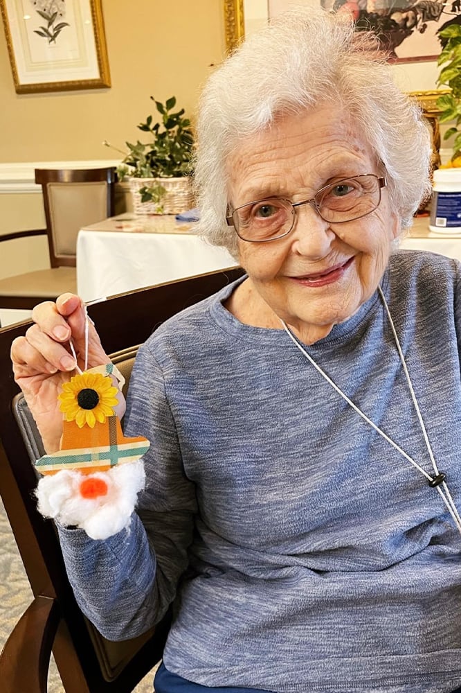 Resident holding a handmade craft in a cozy setting
