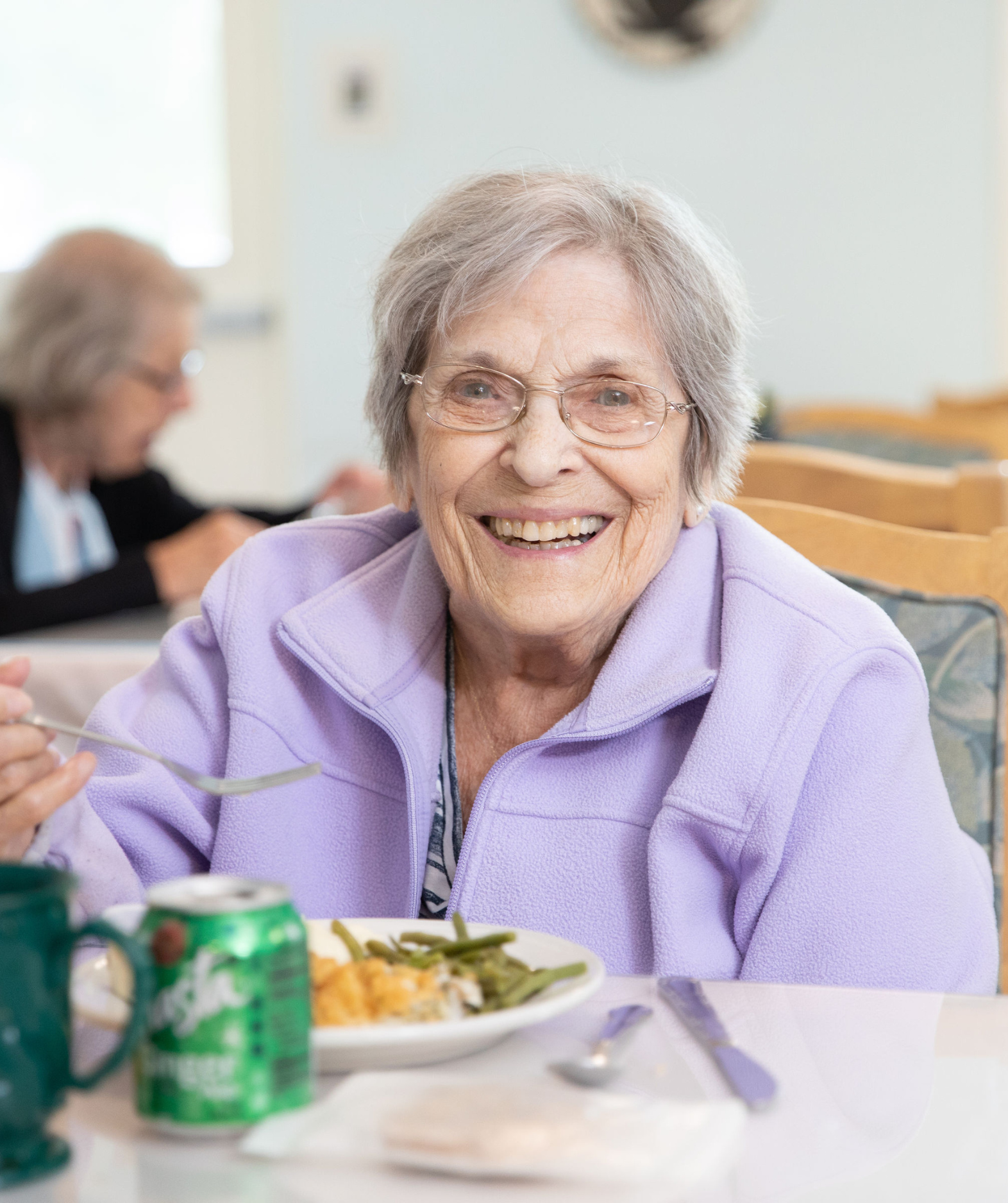 A smiling resident enjoying a meal in a dining area
