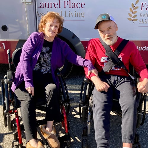 Two residents smiling together in wheelchairs