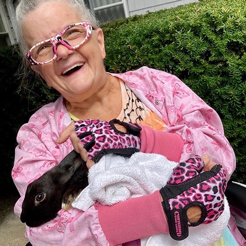Resident joyfully holding a pet rabbit outdoors