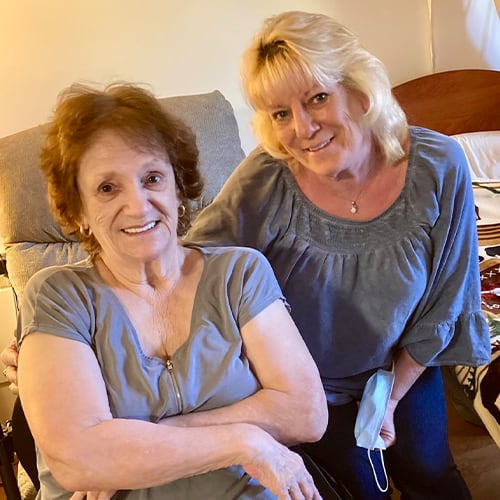 A resident and staff member smiling together in a room