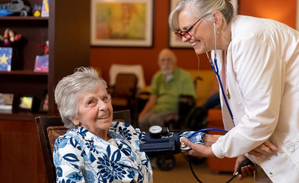 Nurse checking blood pressure of a smiling resident