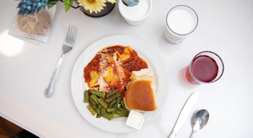 Plate of ravioli with green beans and drinks on a table