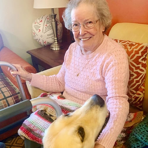 Resident enjoying time with a golden retriever in a cozy living room