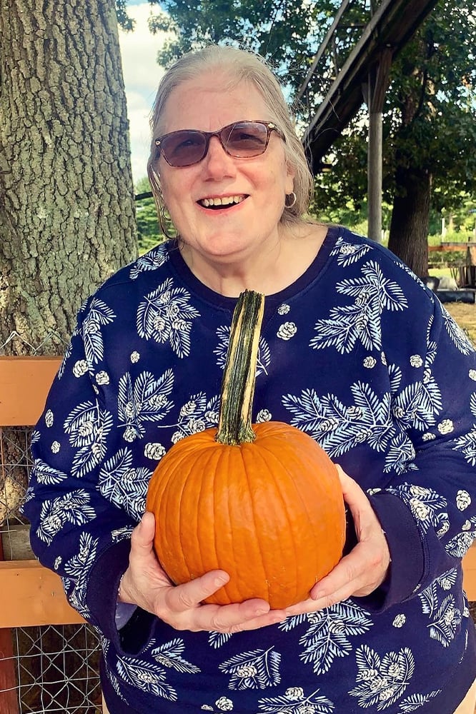 Resident holding a pumpkin outdoors, smiling