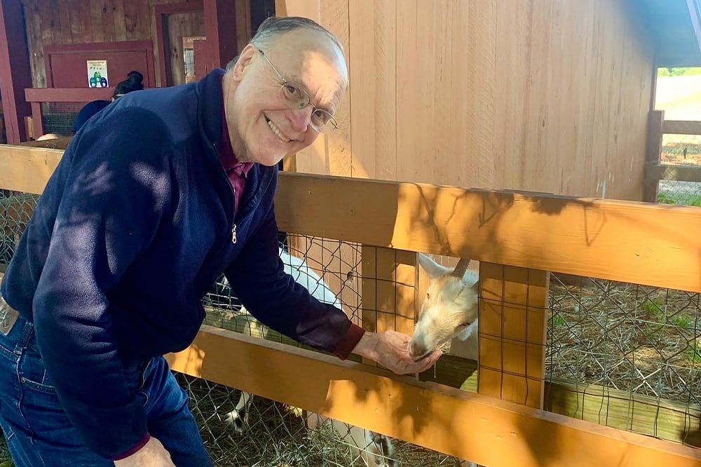 Resident interacting with a goat in an outdoor petting area