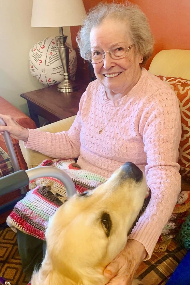 Resident smiling with a dog in her living area