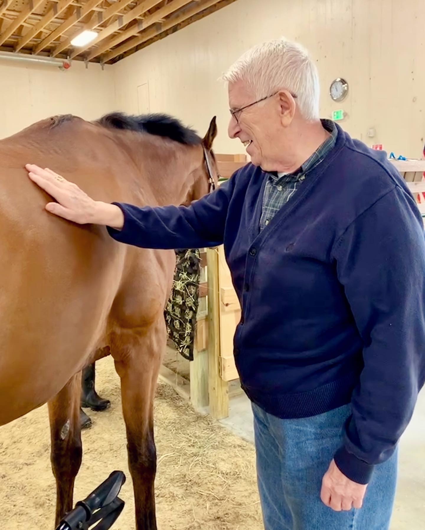 A resident enjoying therapy with a horse indoors