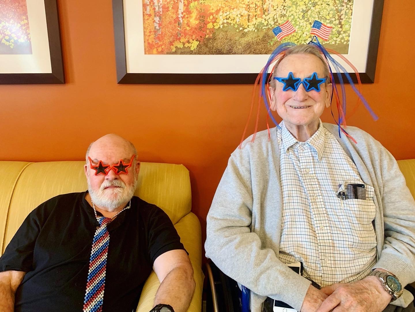 Two residents wearing festive glasses in a cozy lounge.