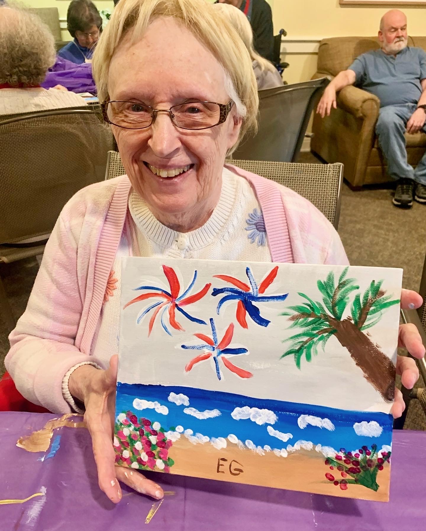 Resident proudly displaying a painting in an activity room