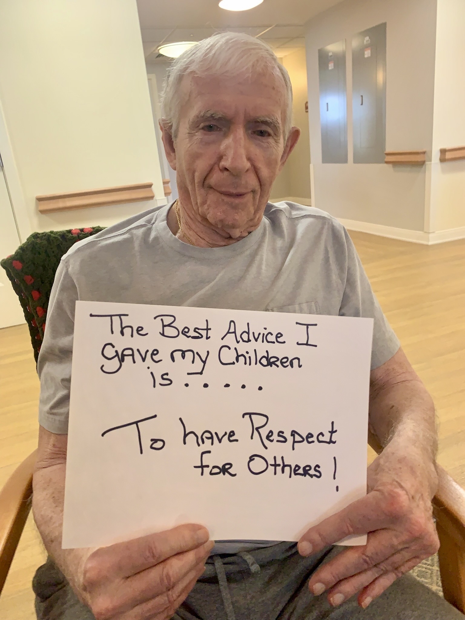 An elderly man holding a sign with advice for his children