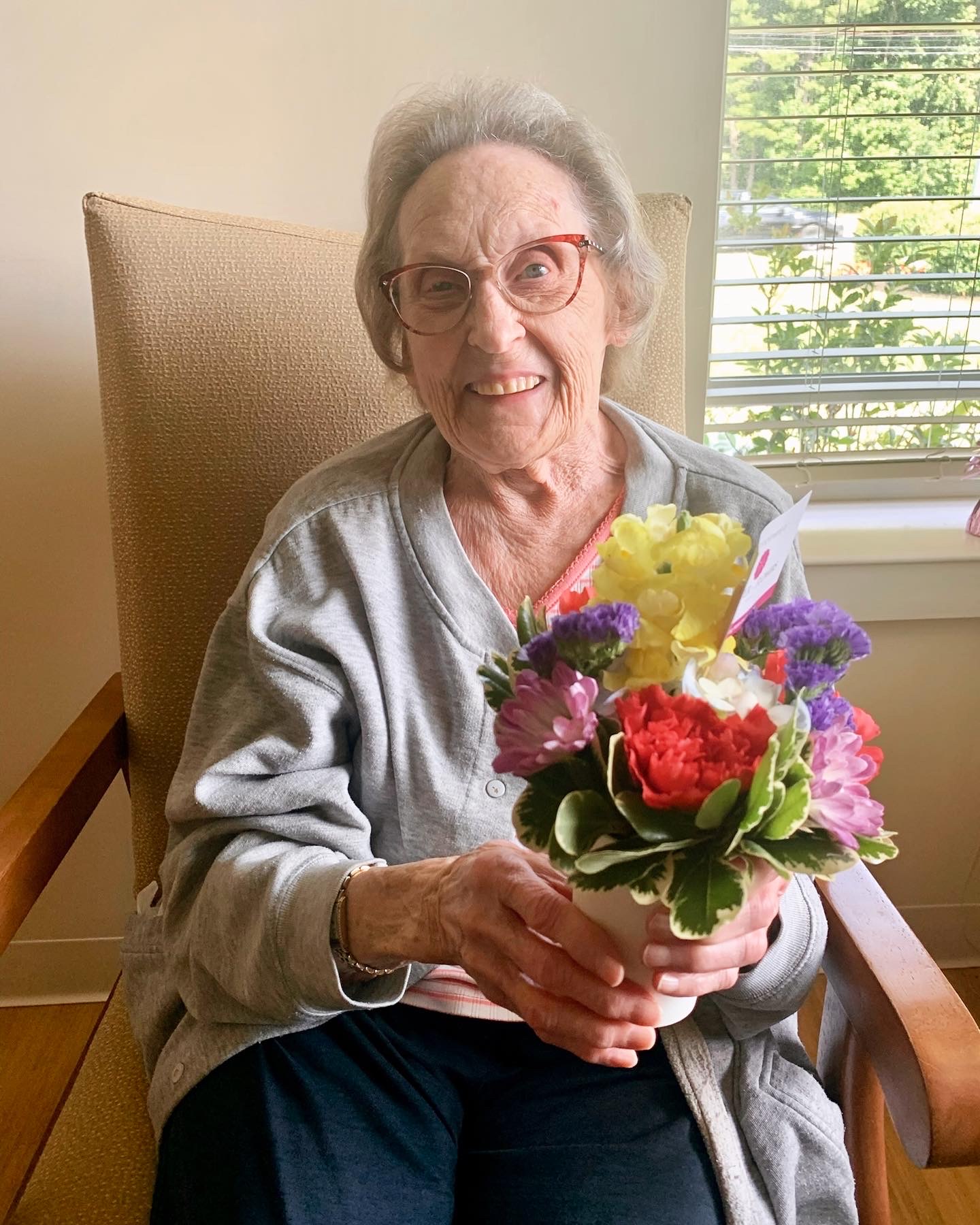 Senior woman holding a flower arrangement, smiling