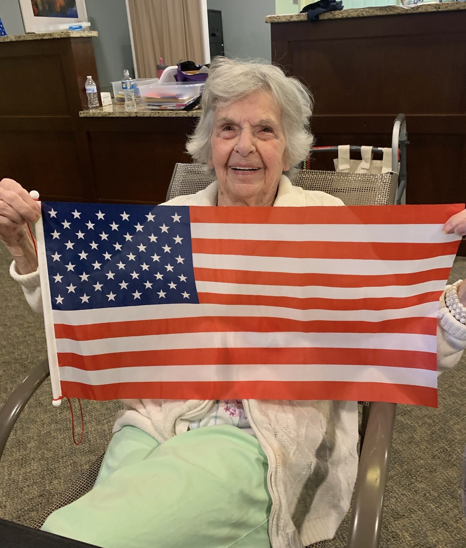 Elderly resident holding an American flag indoors