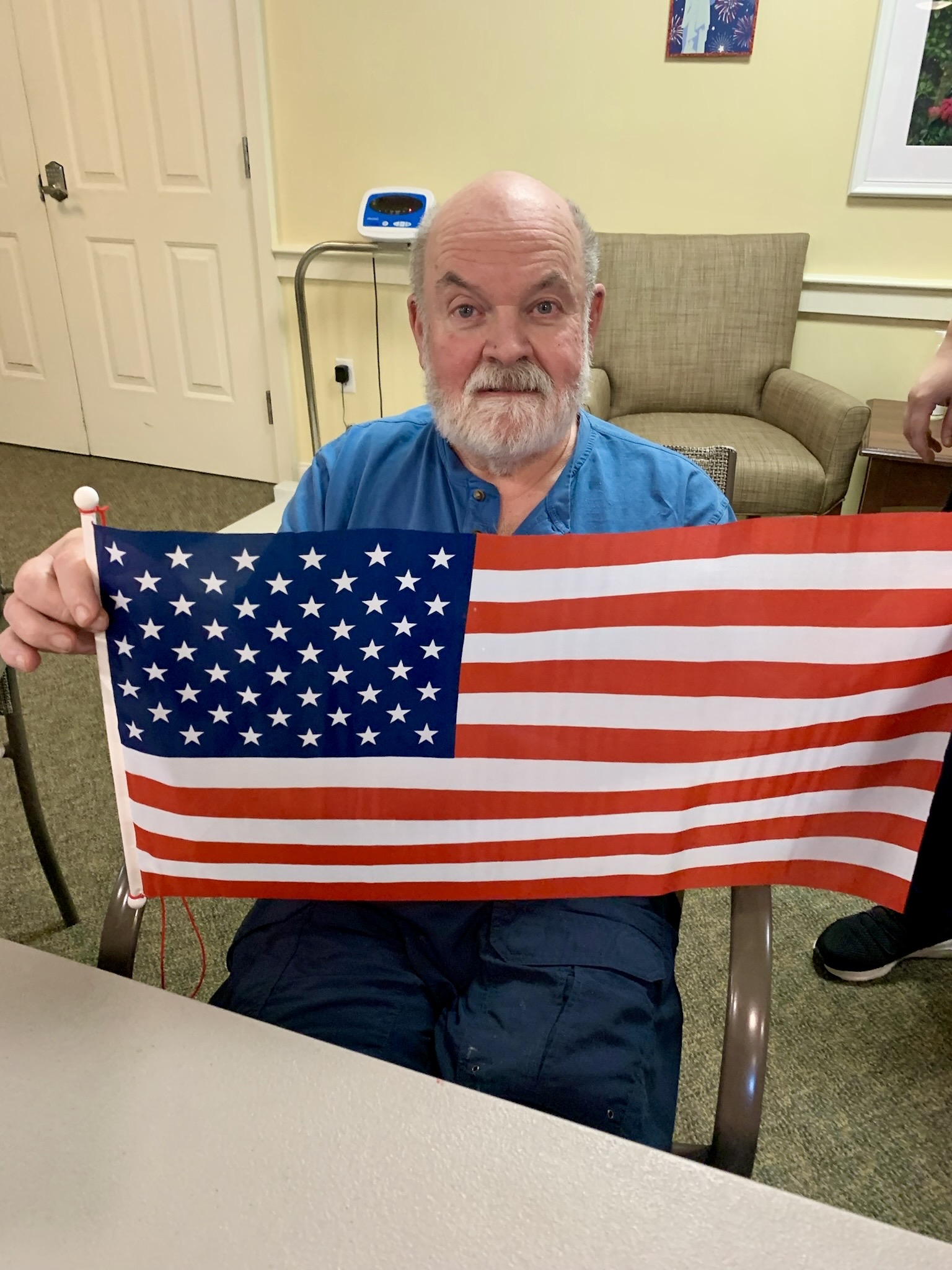 Resident proudly holding an American flag indoors