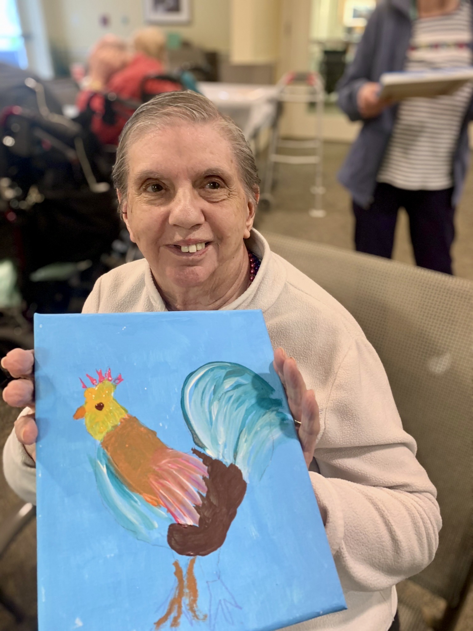 Resident holding a colorful painting of a chicken