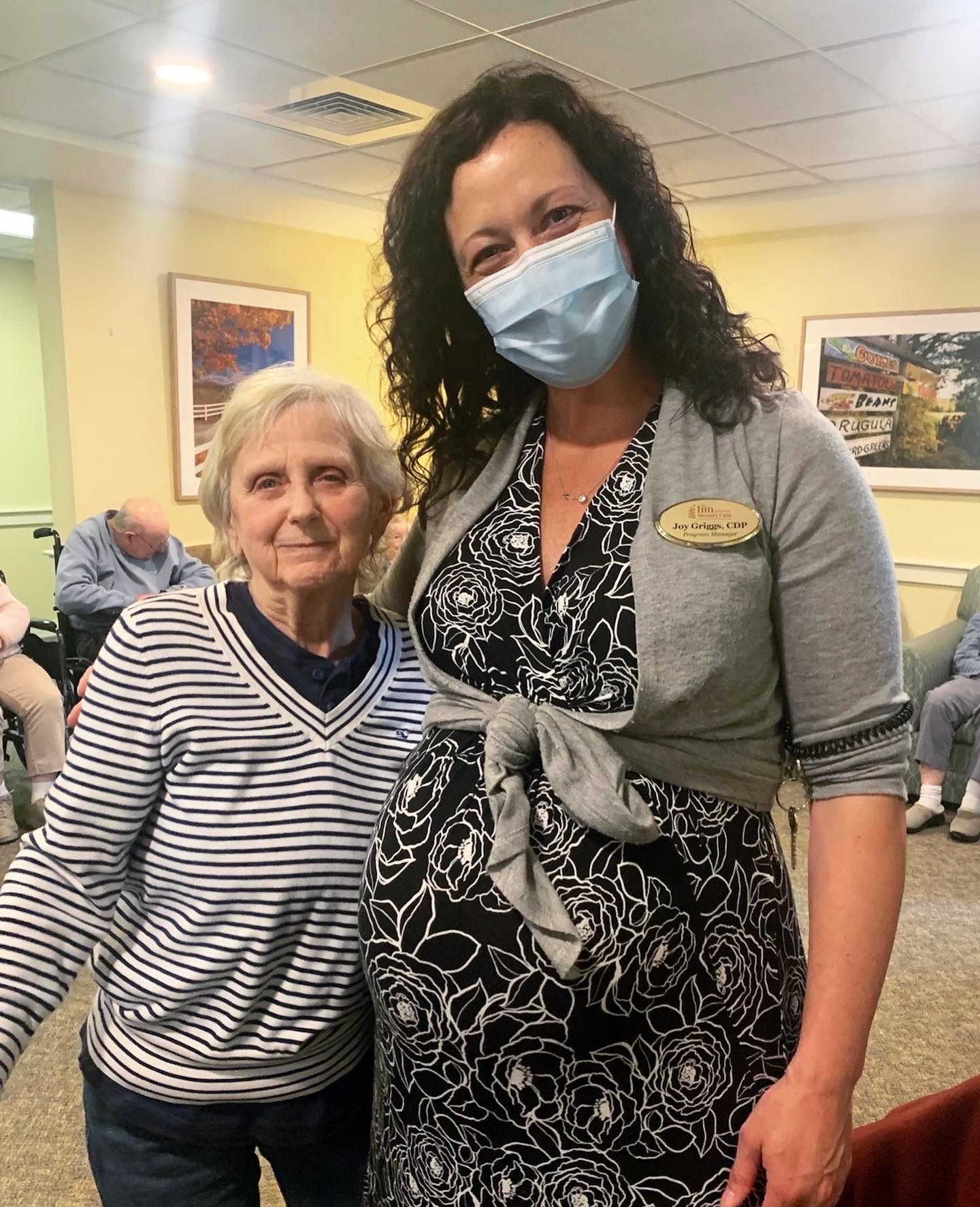 A staff member posing with a resident in an activity space.