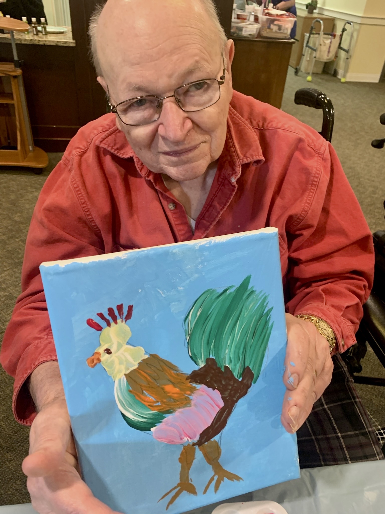 Resident showing a colorful painting of a rooster