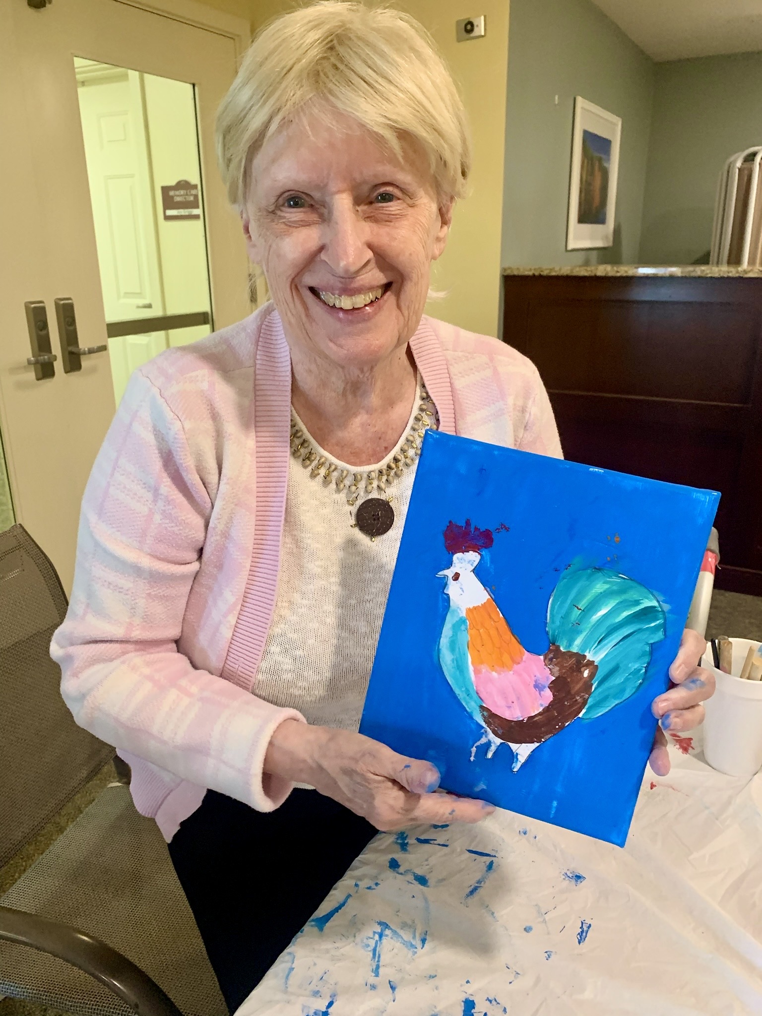 Resident proudly displaying her painting in an activity room