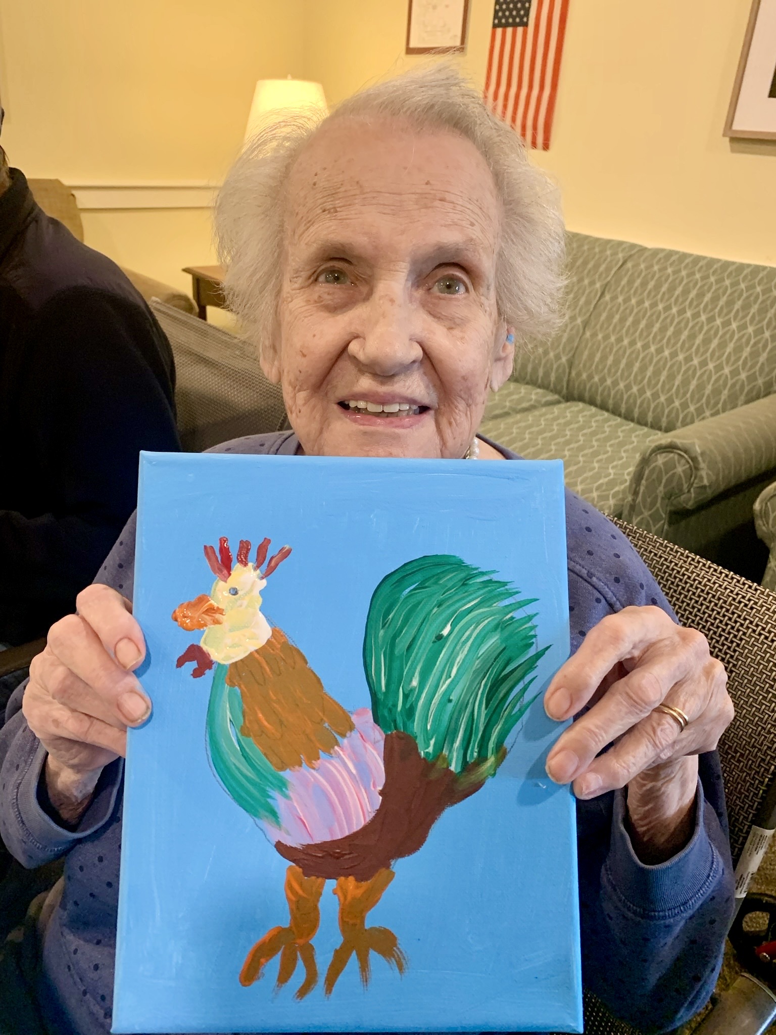 Resident holding a painted rooster artwork