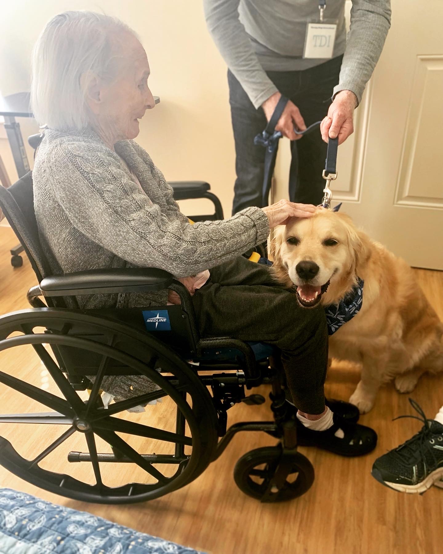 Resident smiling with therapy dog in a wheelchair