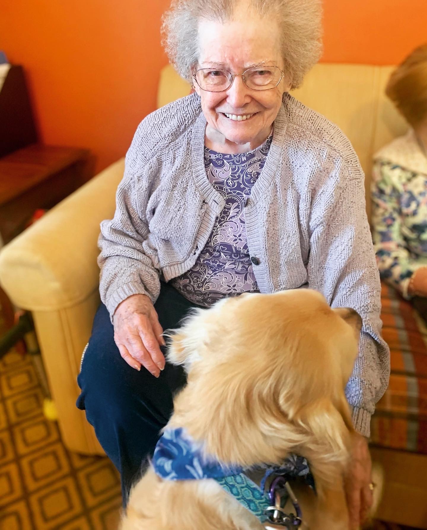 Resident smiling with a golden retriever in a cozy setting