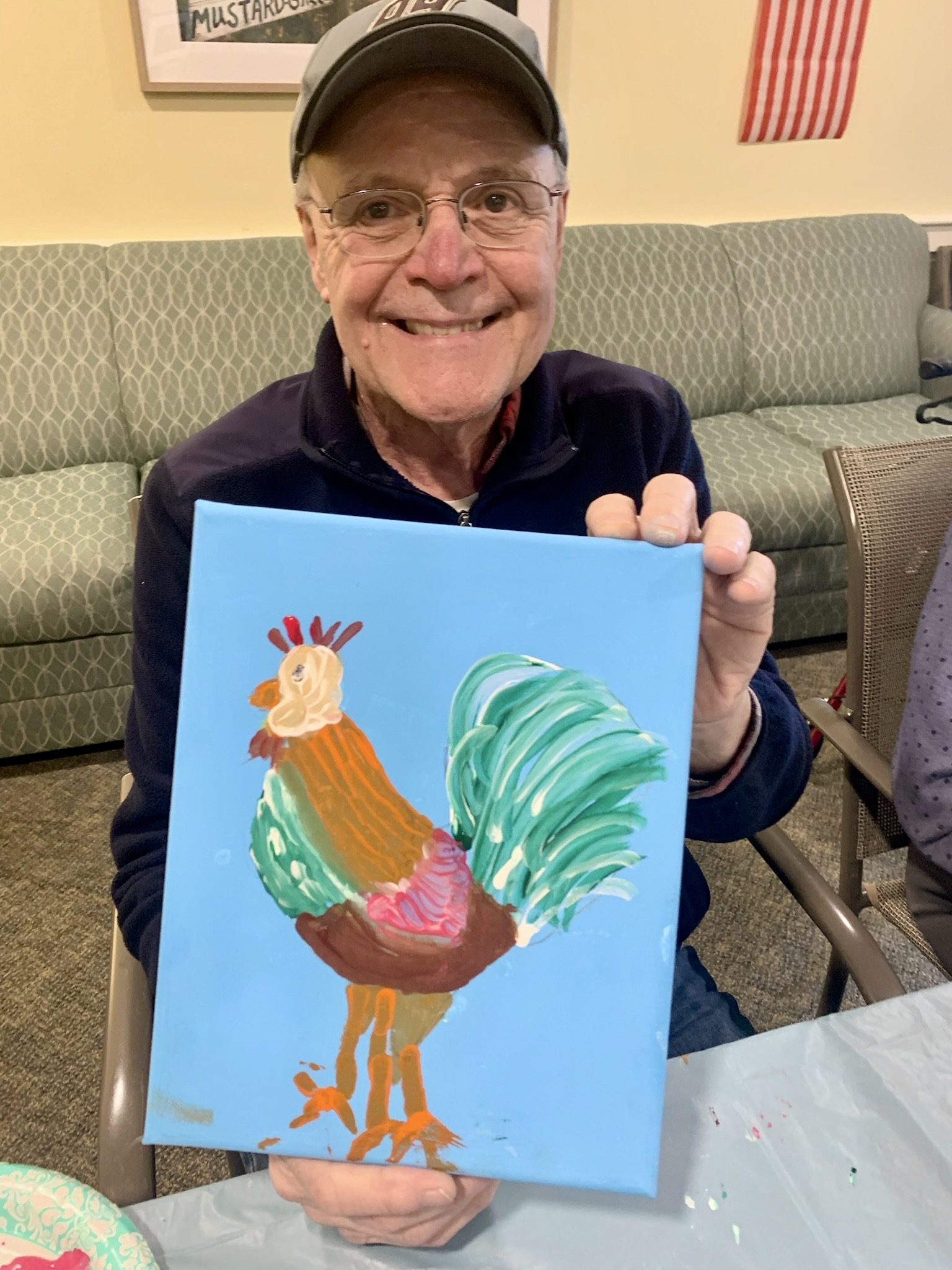 Resident proudly holding a painted rooster artwork