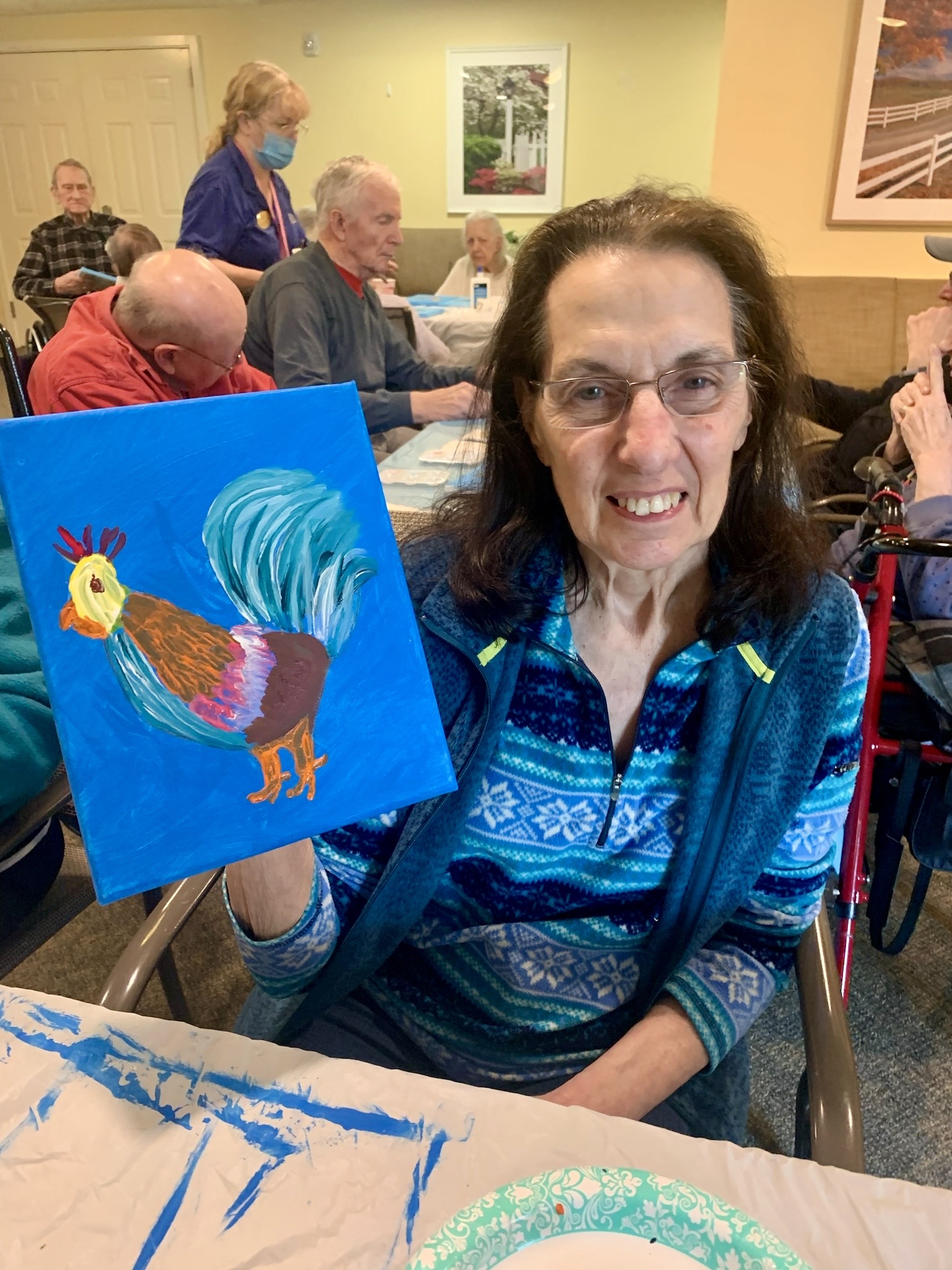 Resident holding a painted rooster in an activity room
