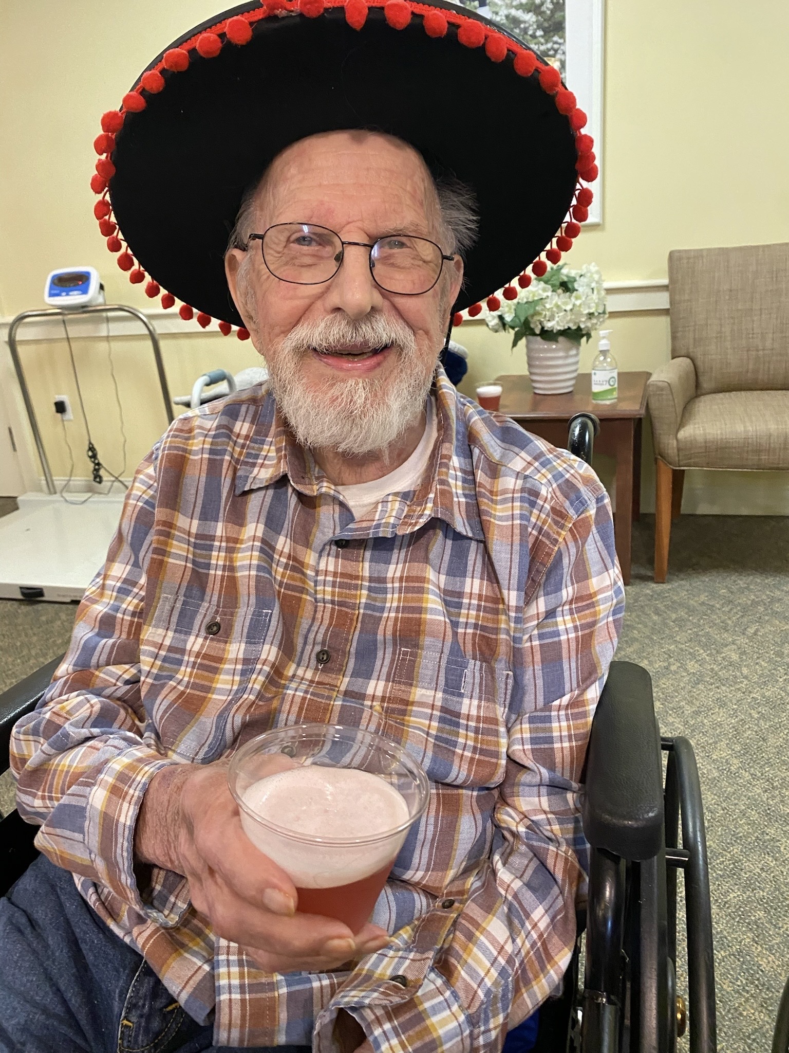 Resident celebrating with a drink in a festive hat