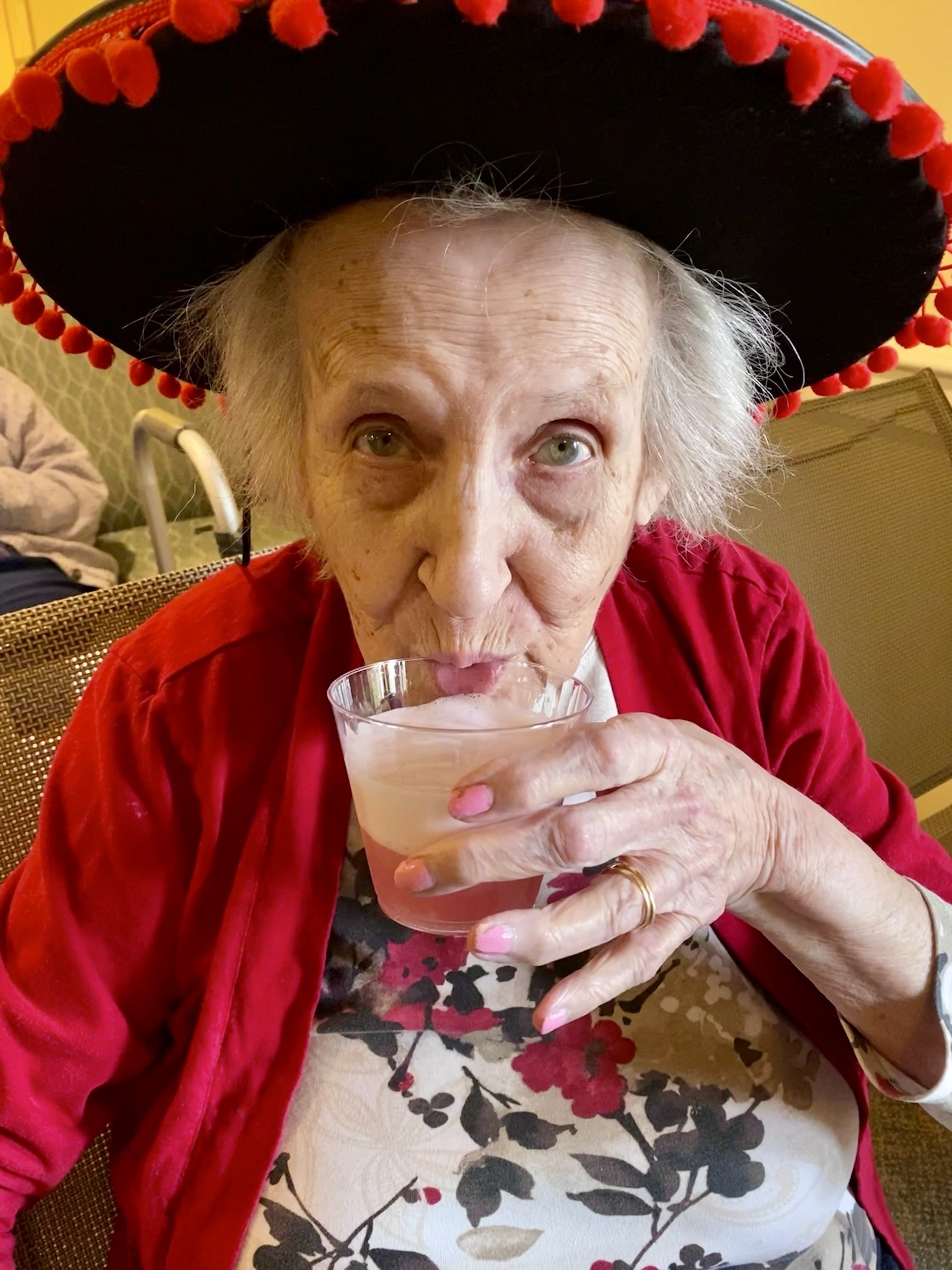 Elderly resident in a festive hat enjoying a drink