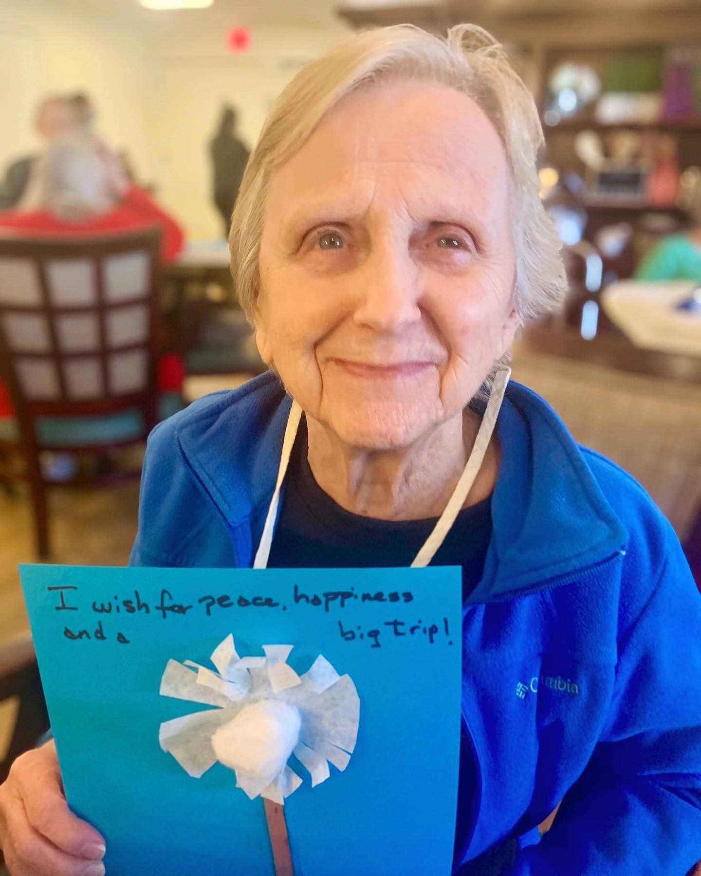 Resident holding a colorful handmade card in a common area