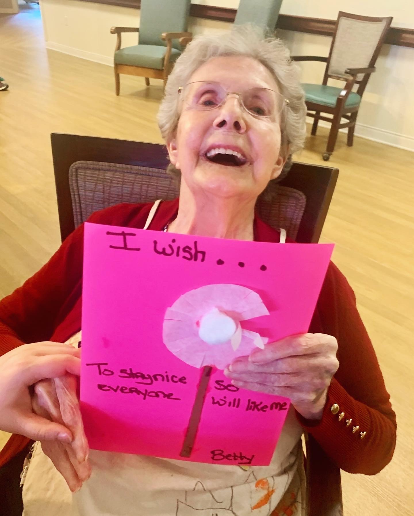 Resident holding a colorful craft project with a big smile