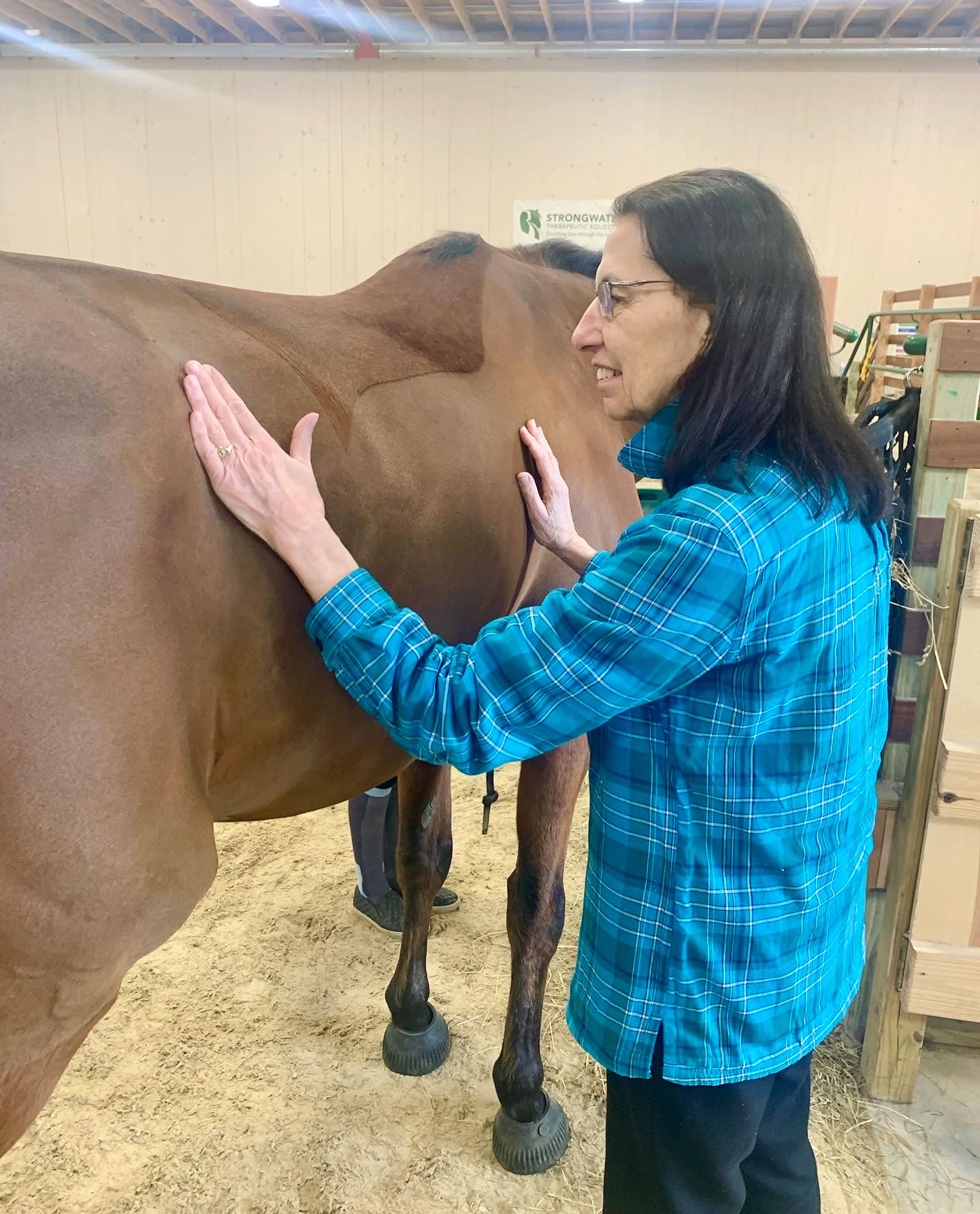 A resident interacting with a horse in an indoor setting