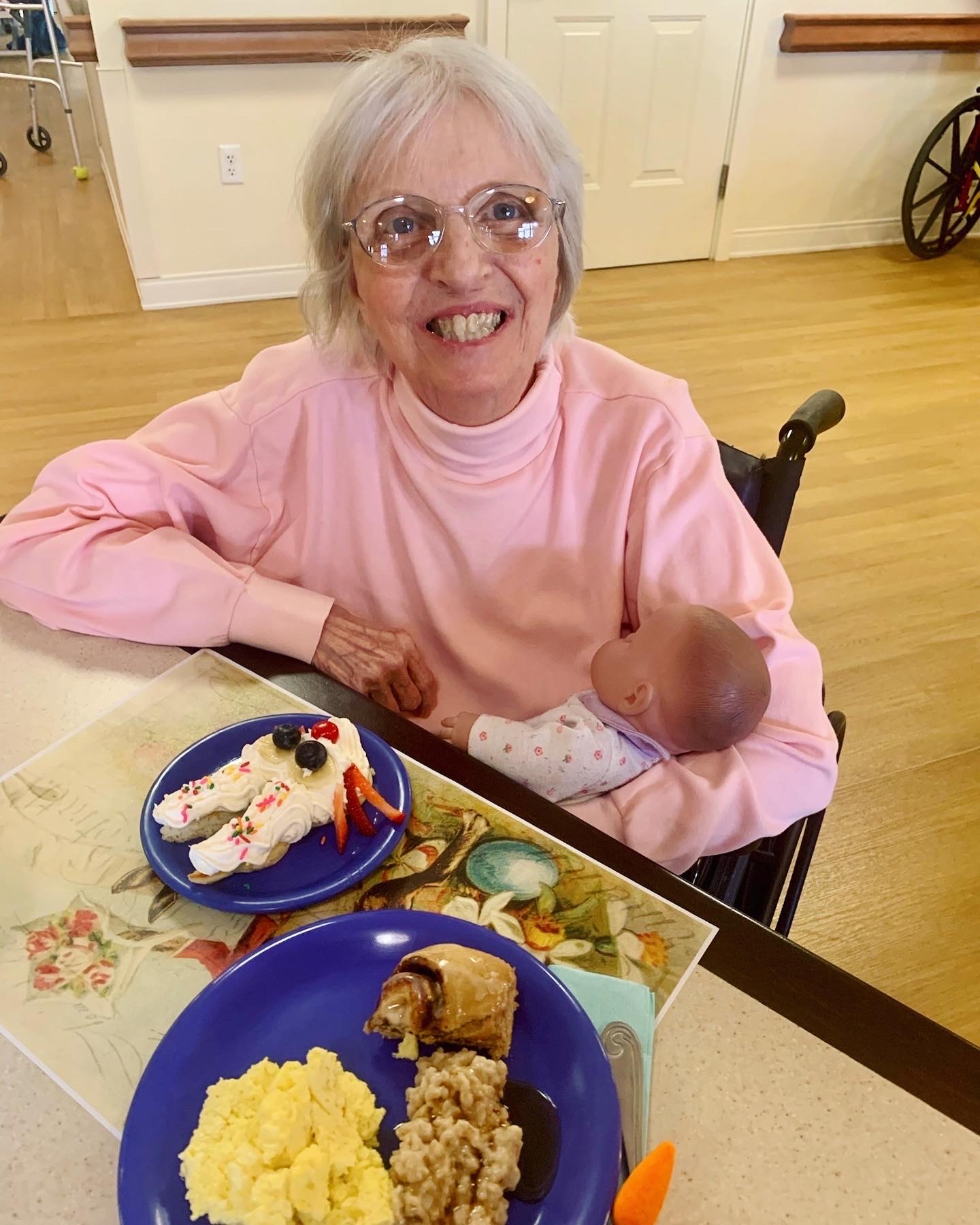 Resident enjoying a meal with a doll