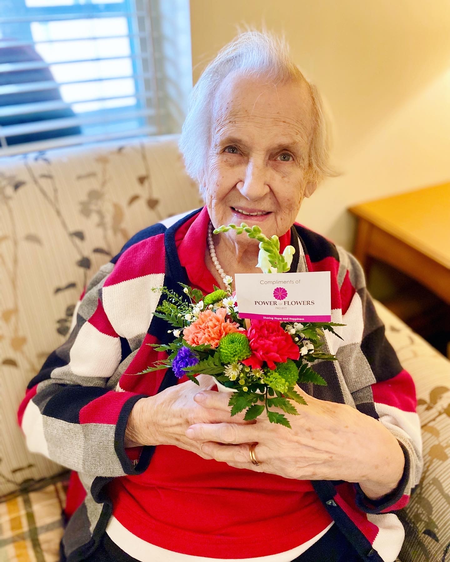 Resident holding a flower arrangement with a smile