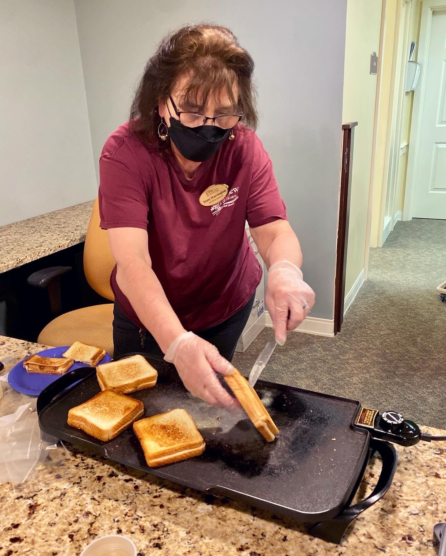 Staff member preparing grilled cheese sandwiches in kitchen