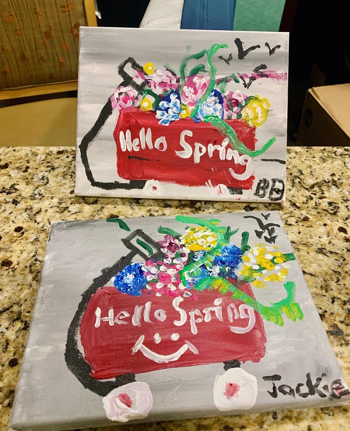 Two painted artworks with flowers in a red wagon