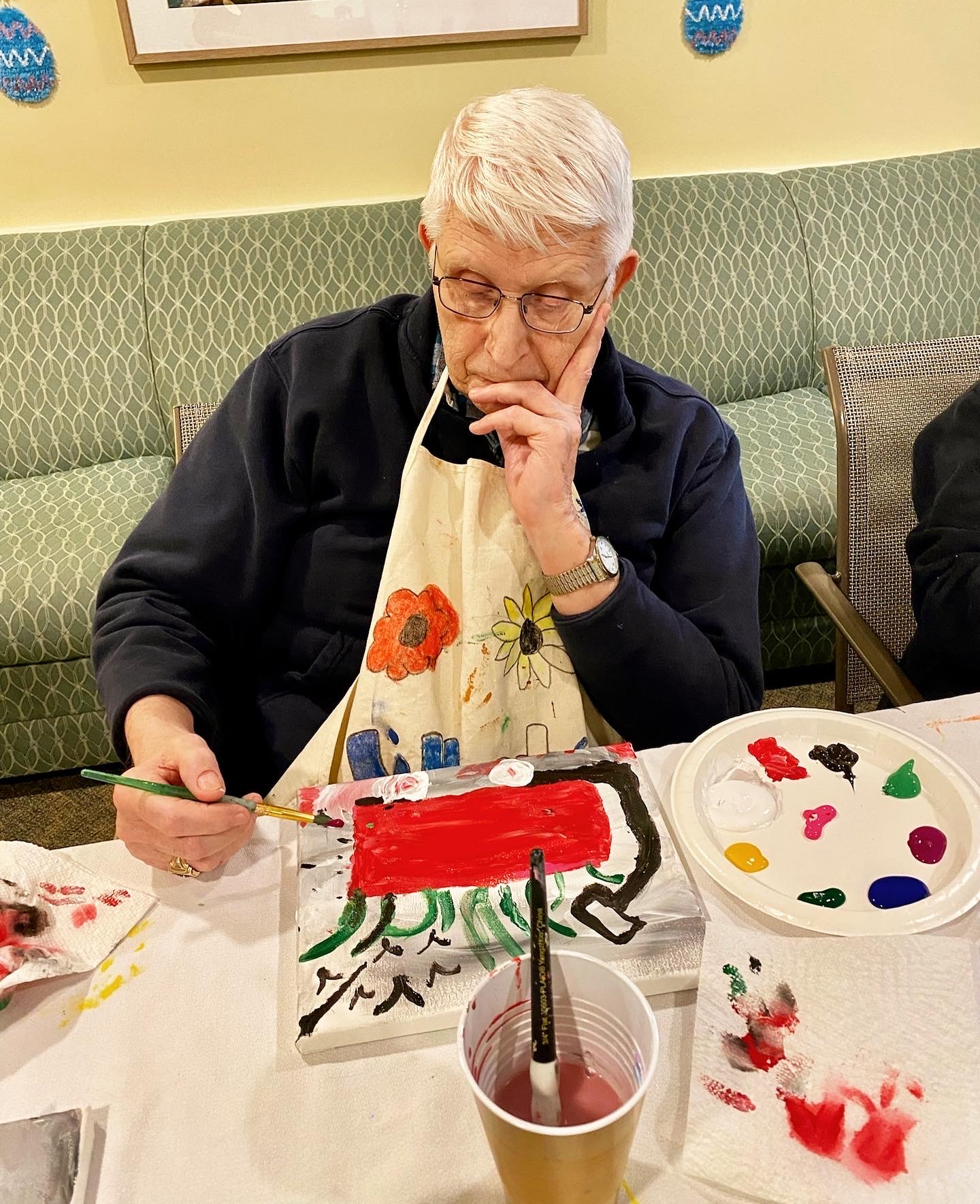 A resident painting at an activity table during arts and crafts