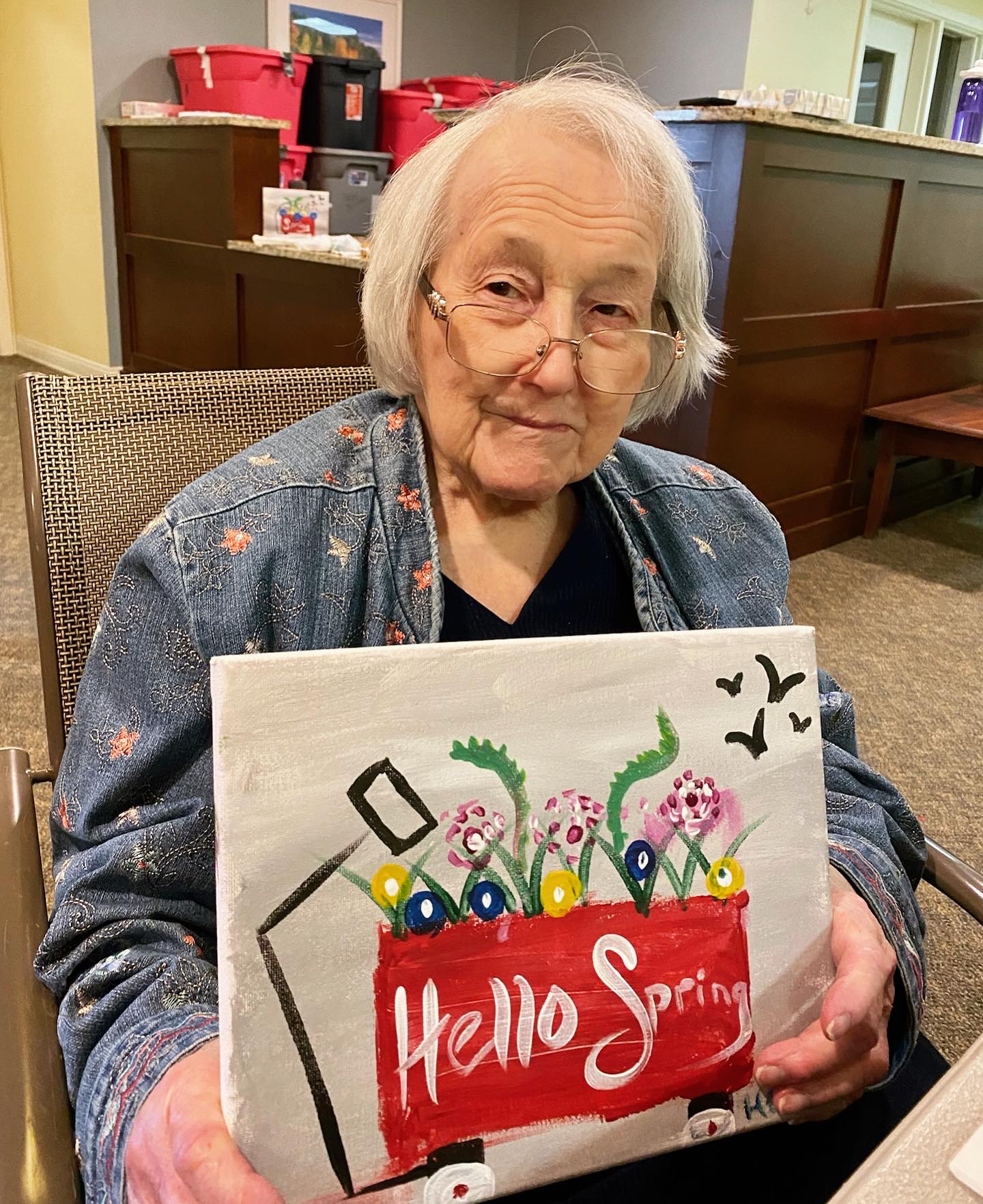 Resident showcasing spring-themed painting in an interior setting