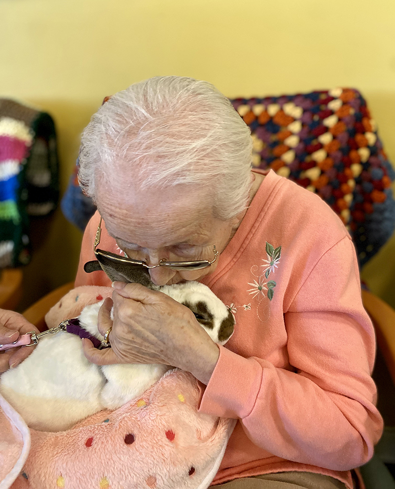 An elderly woman cuddling a rabbit in a cozy setting