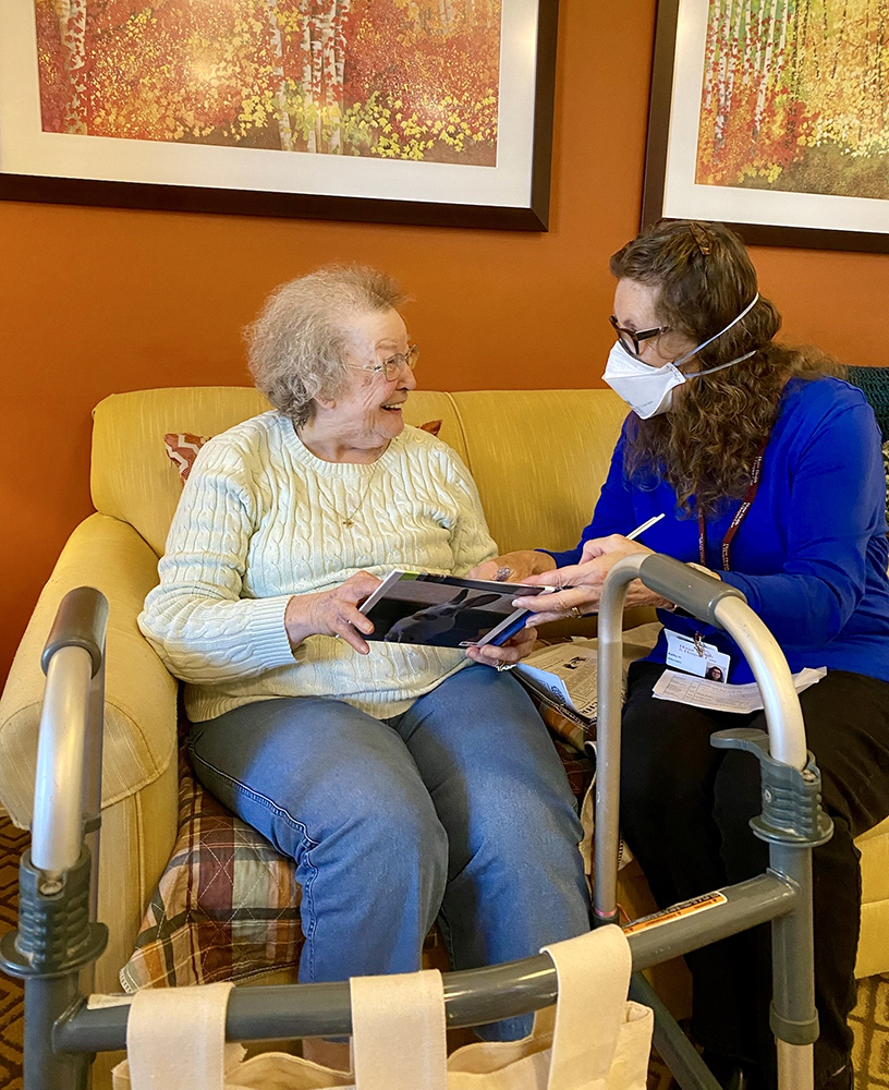 A caregiver assisting a resident with a tablet