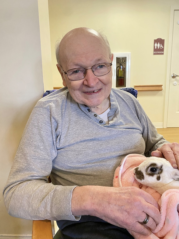 Resident holding a rabbit in a cozy interior setting