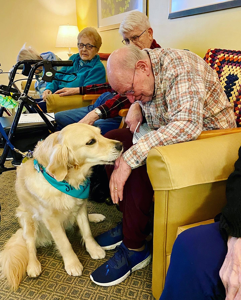 Residents interacting with a therapy dog in a common area