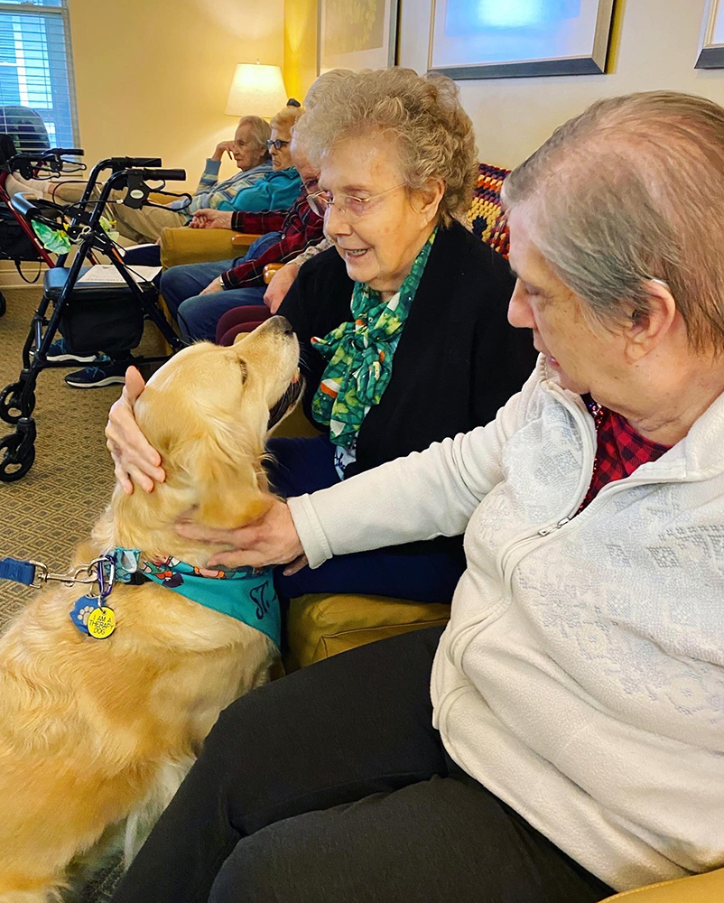 Residents interacting with a therapy dog in a common area
