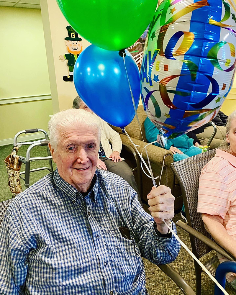An elderly man celebrating with balloons in a social setting