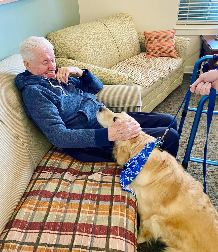 Resident interacting with a therapy dog in a common area