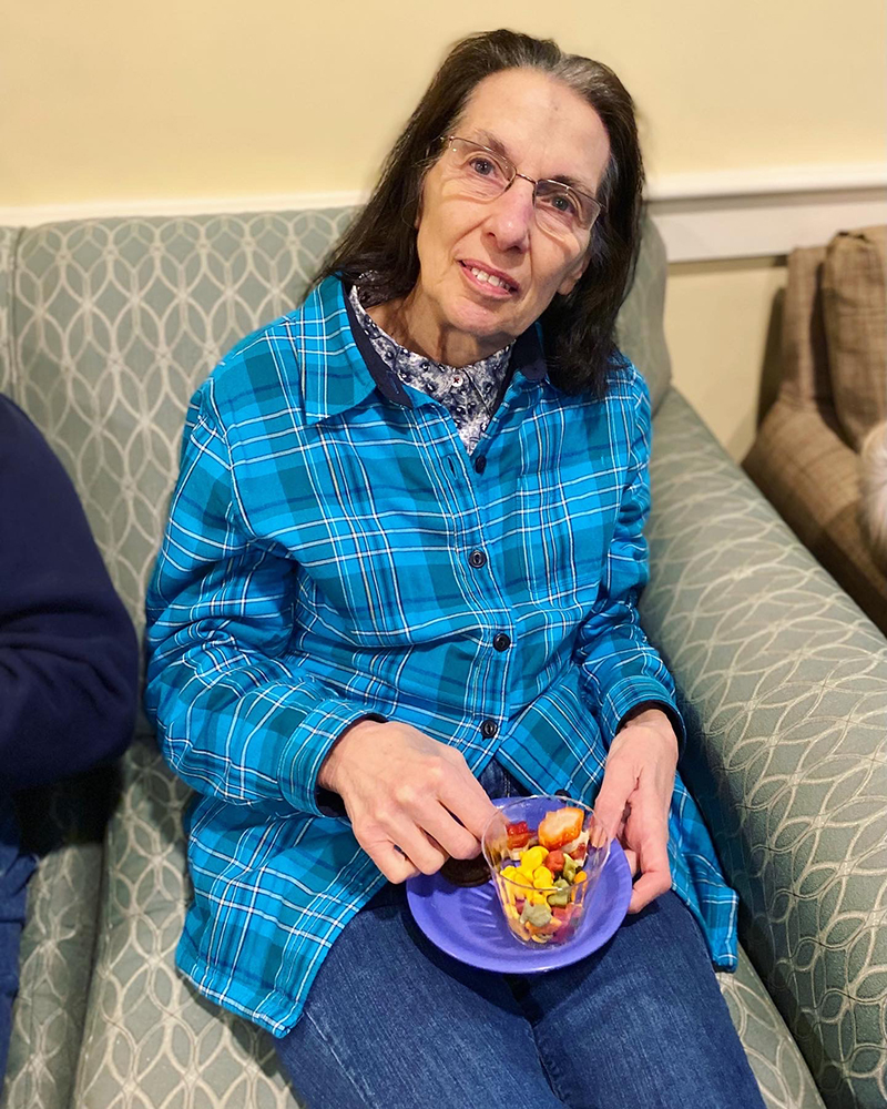 Resident enjoying a colorful snack in a cozy chair