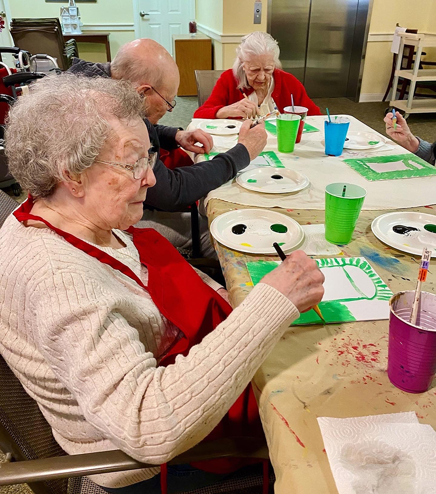 Residents engaged in a painting activity at a table