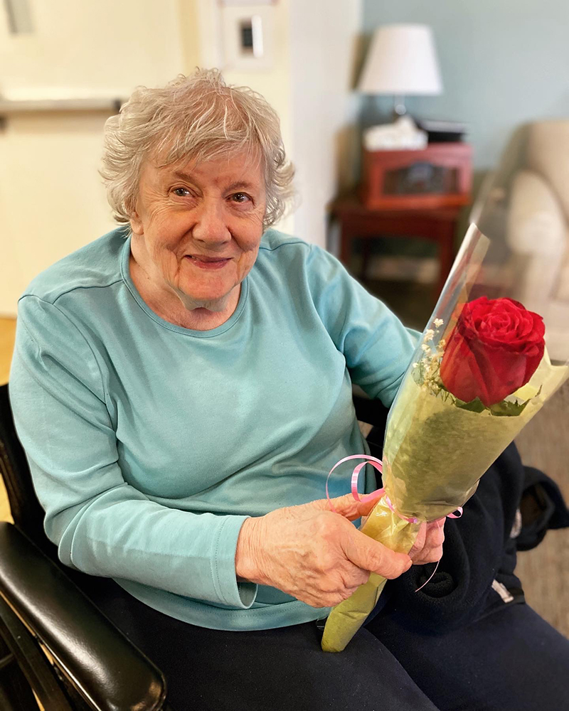 Senior resident holding a single red rose.