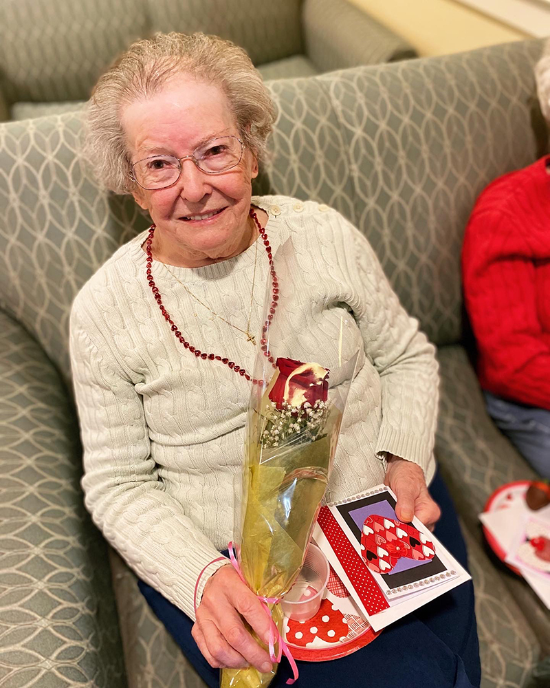 Resident holding a flower and card in a cozy common area